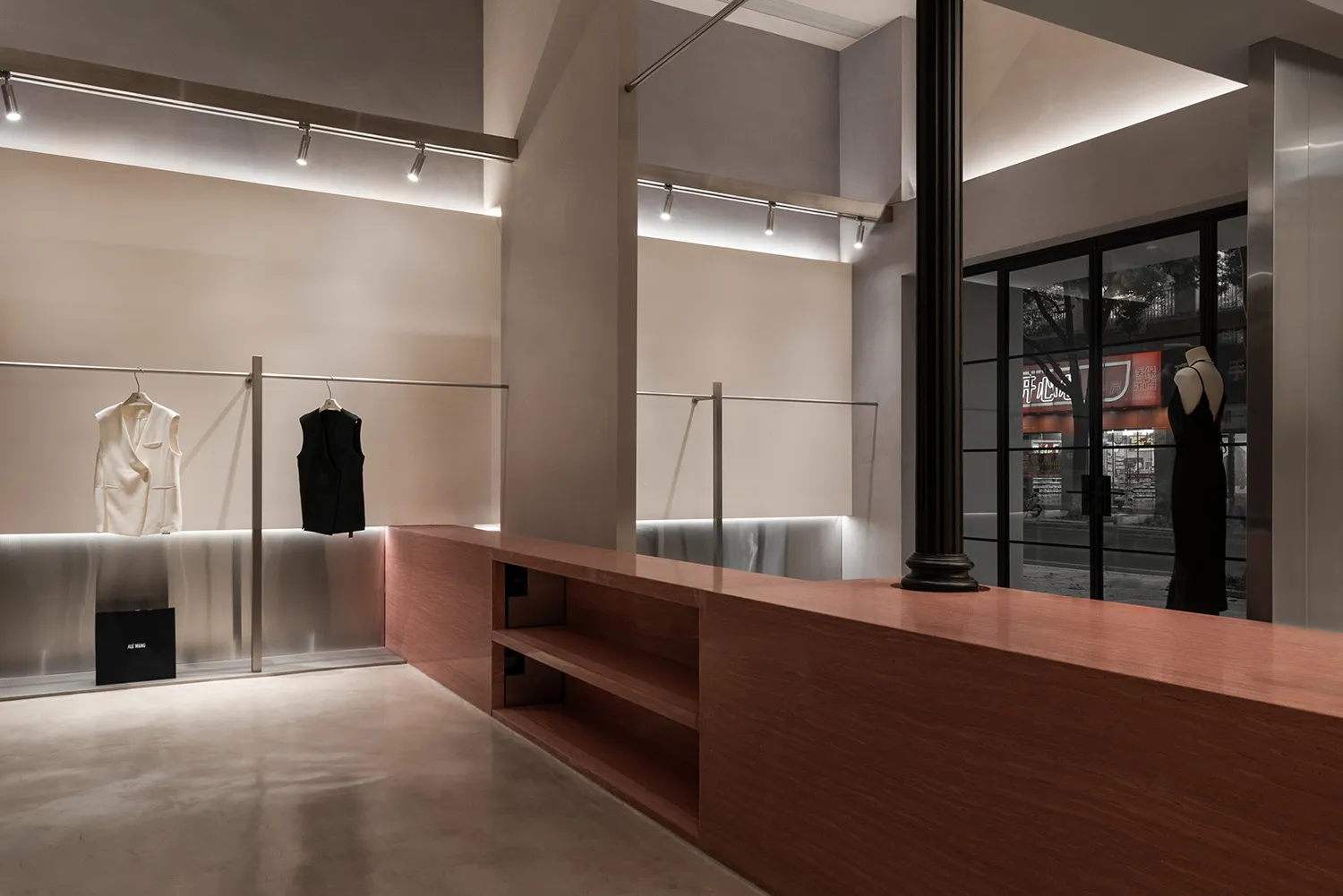 現代零售店內部，展示金屬、玻璃與木質面板製成的服裝展示架。