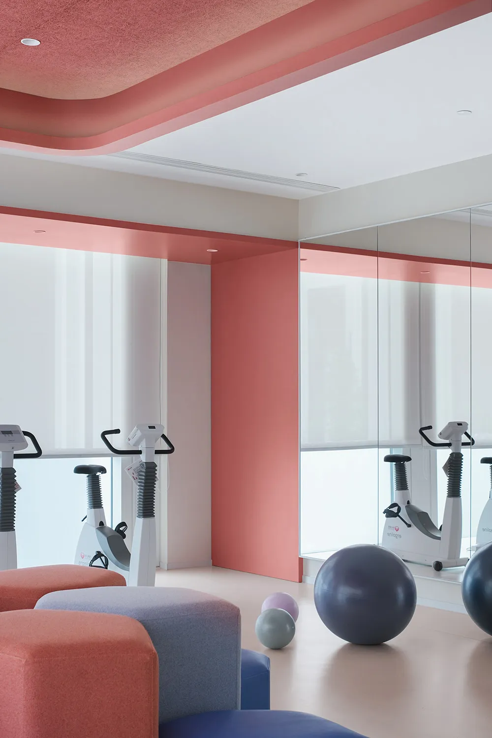 Minimalist-style gym space with exercise bikes, workout balls, and ombre-colored seating.