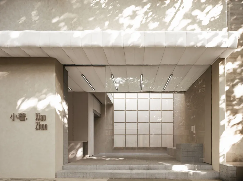 A minimalist retail storefront with concrete walls and a glass façade.
