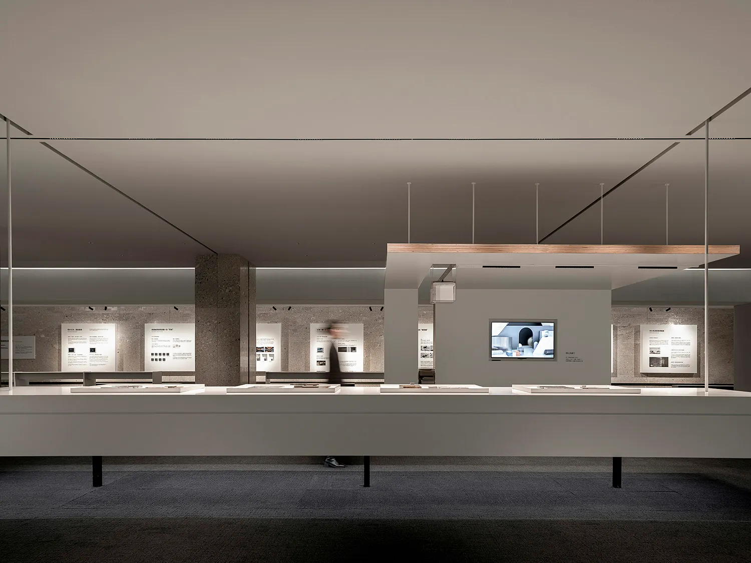 Minimalist exhibition space featuring concrete, glass, and metal materials.