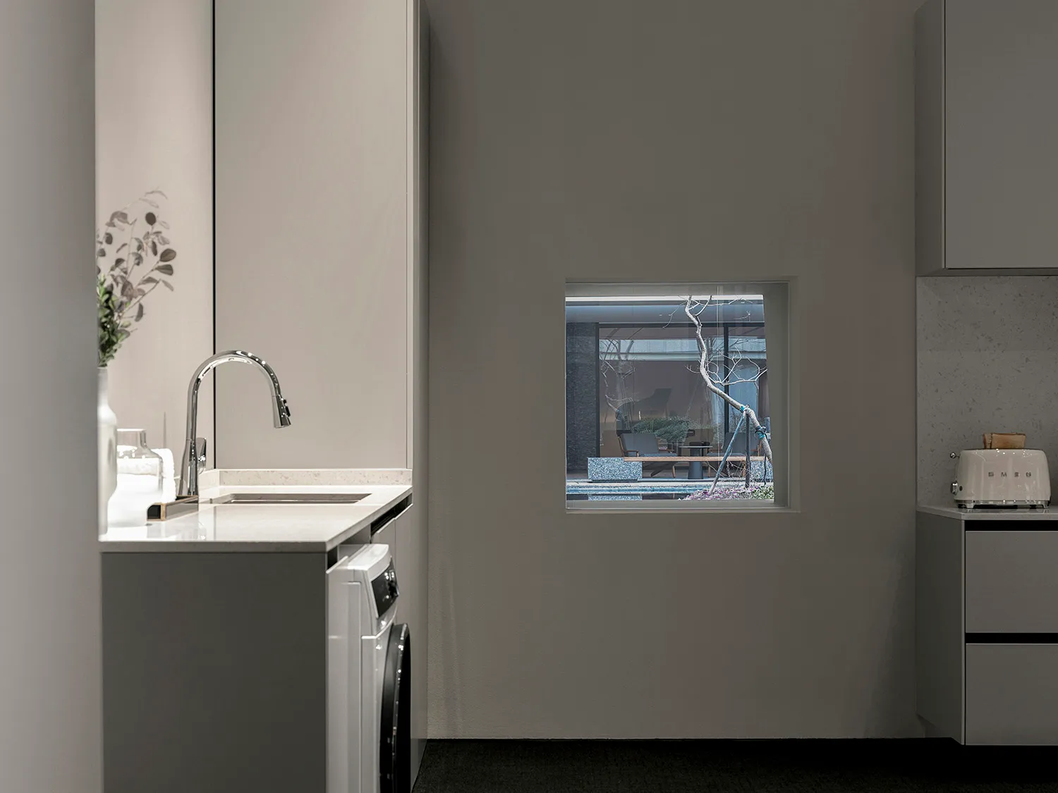 Modern kitchen with marble countertop and sink, featuring a window looking out to a pool and outdoor seating area.