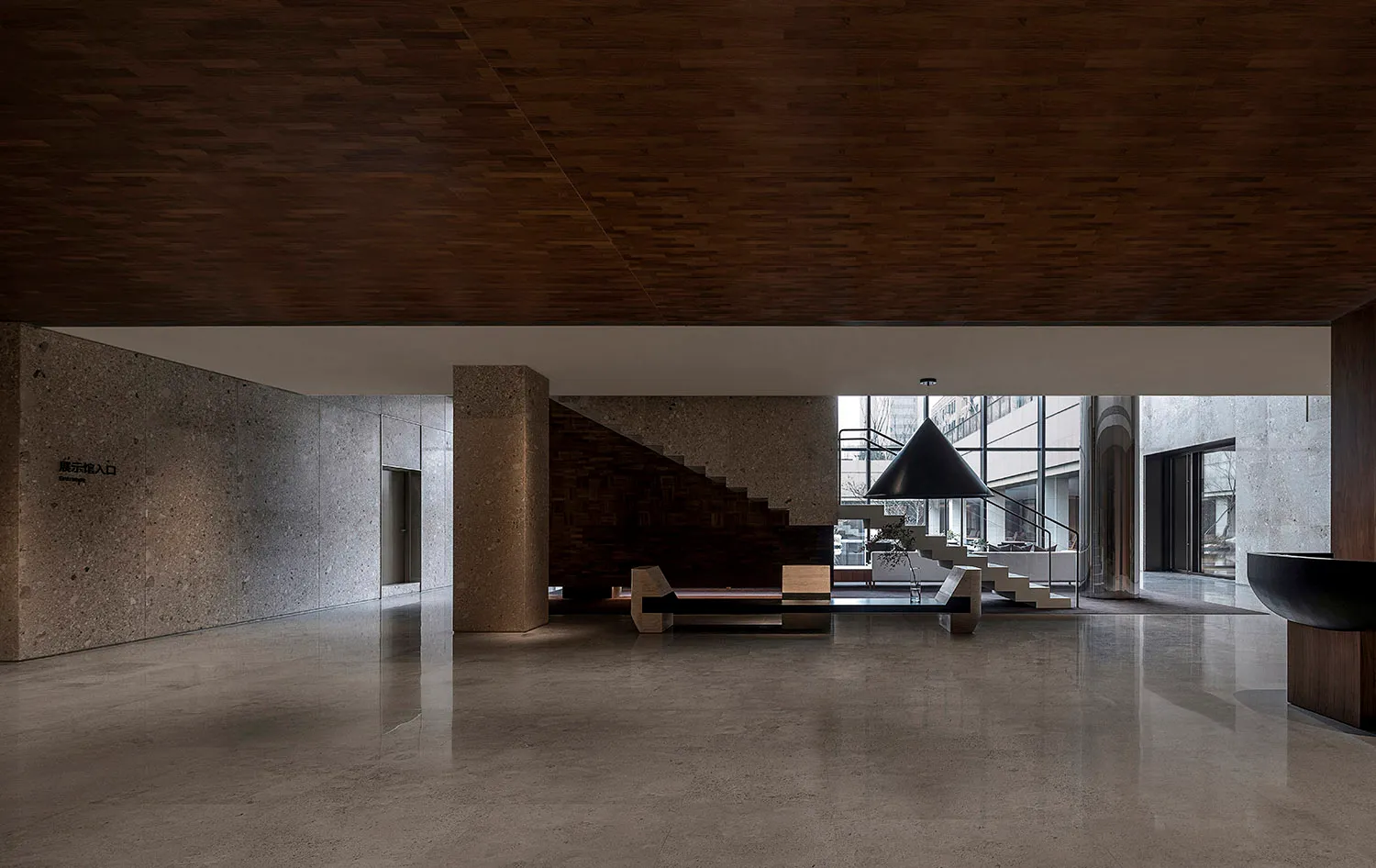 A modern office interior with concrete walls and flooring, featuring a wooden ceiling and a large black lamp.