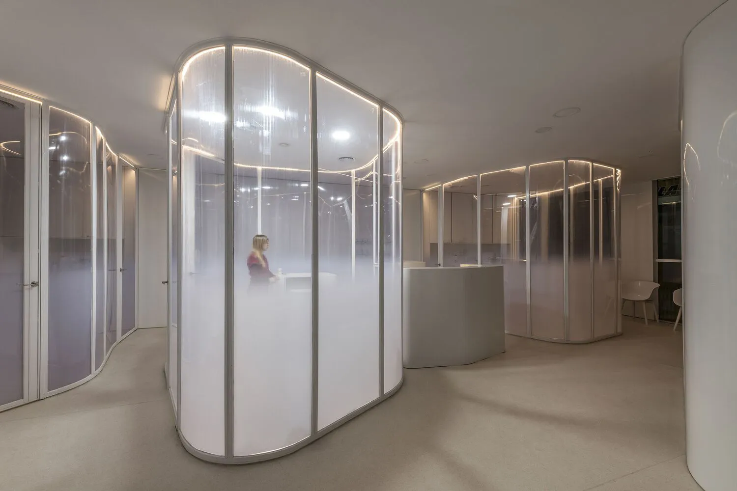 A modern office space featuring glass walls and partitions.
