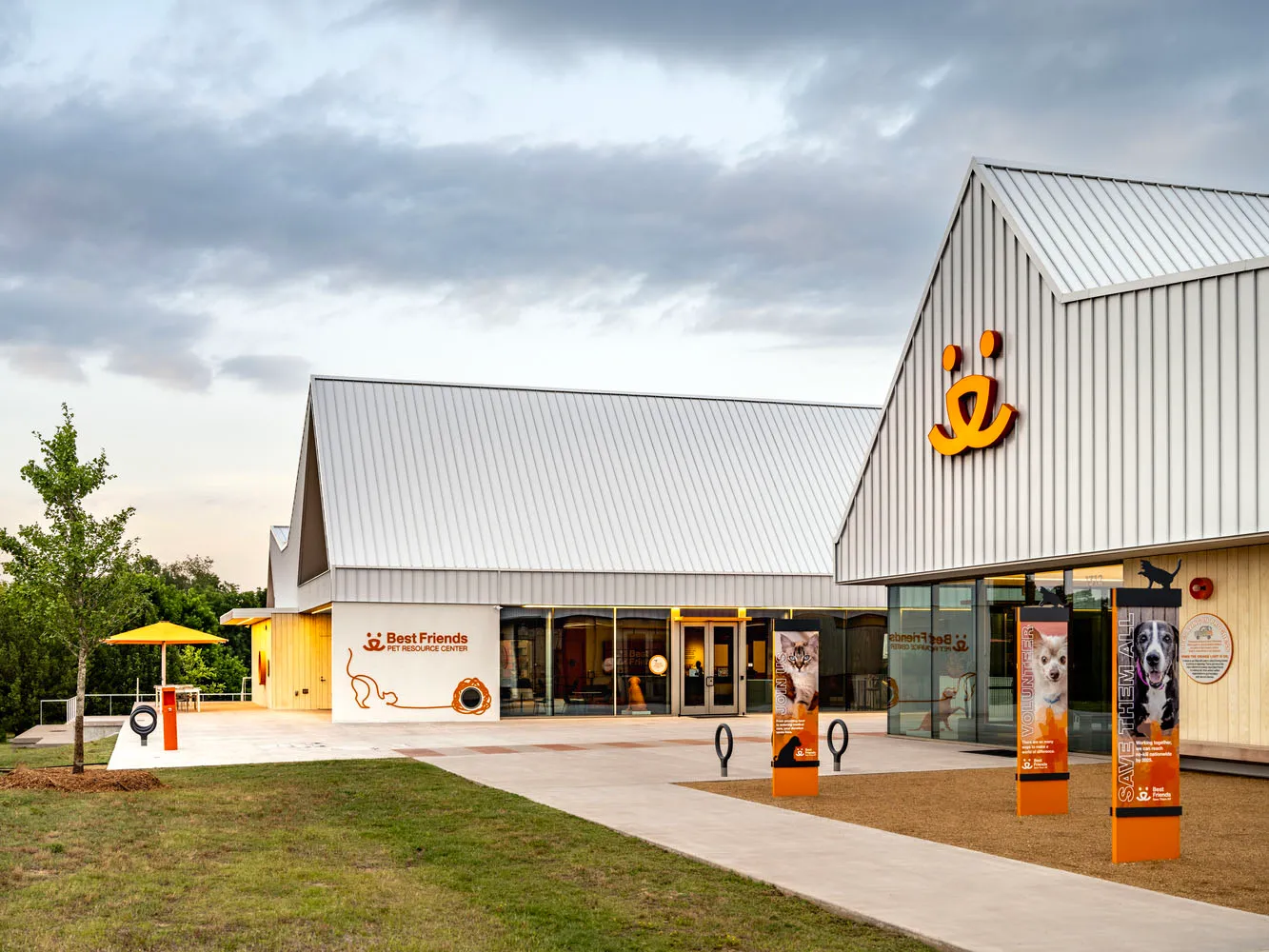 Modern, metal-clad exterior of a pet resource center with a sign featuring a cat and dog.