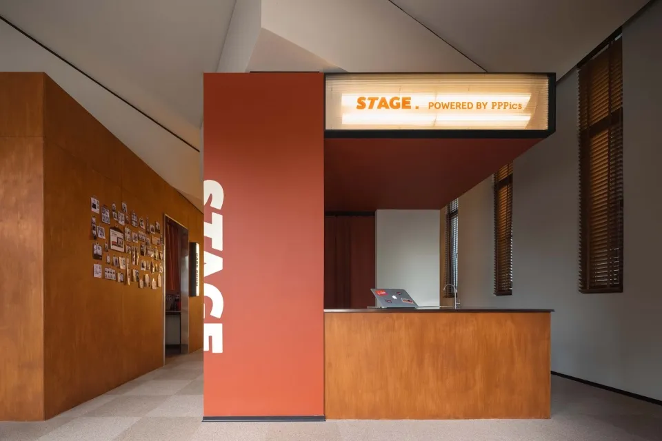Modern interior design featuring a wooden reception desk with a stage area illuminated by a sign.