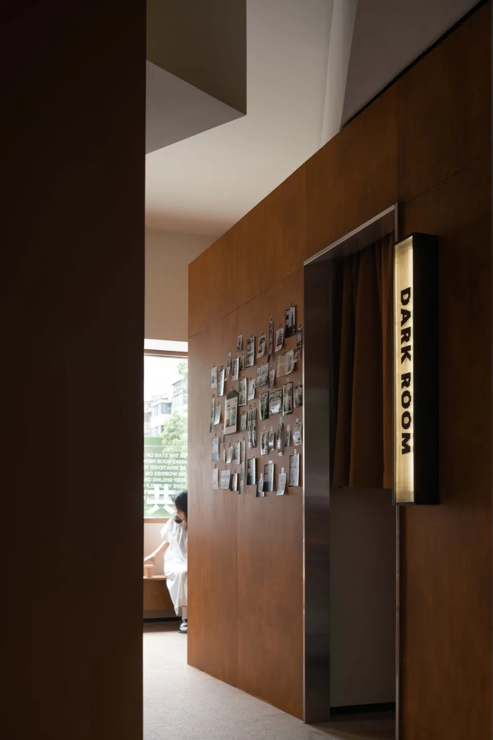 A dark room with wooden paneled walls featuring a collection of framed photographs on the left wall.