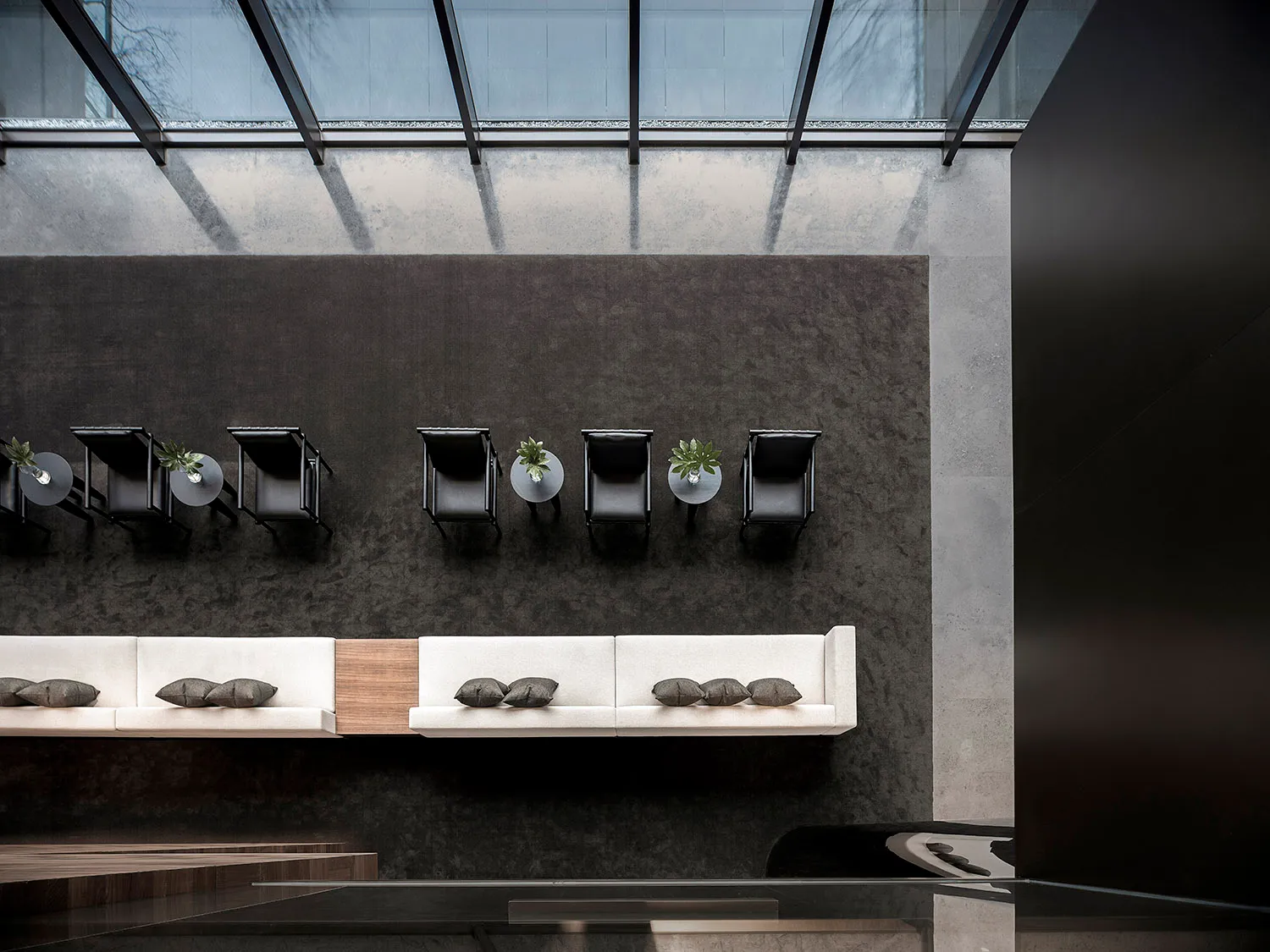Modern office lounge area with concrete walls and glass partitions.