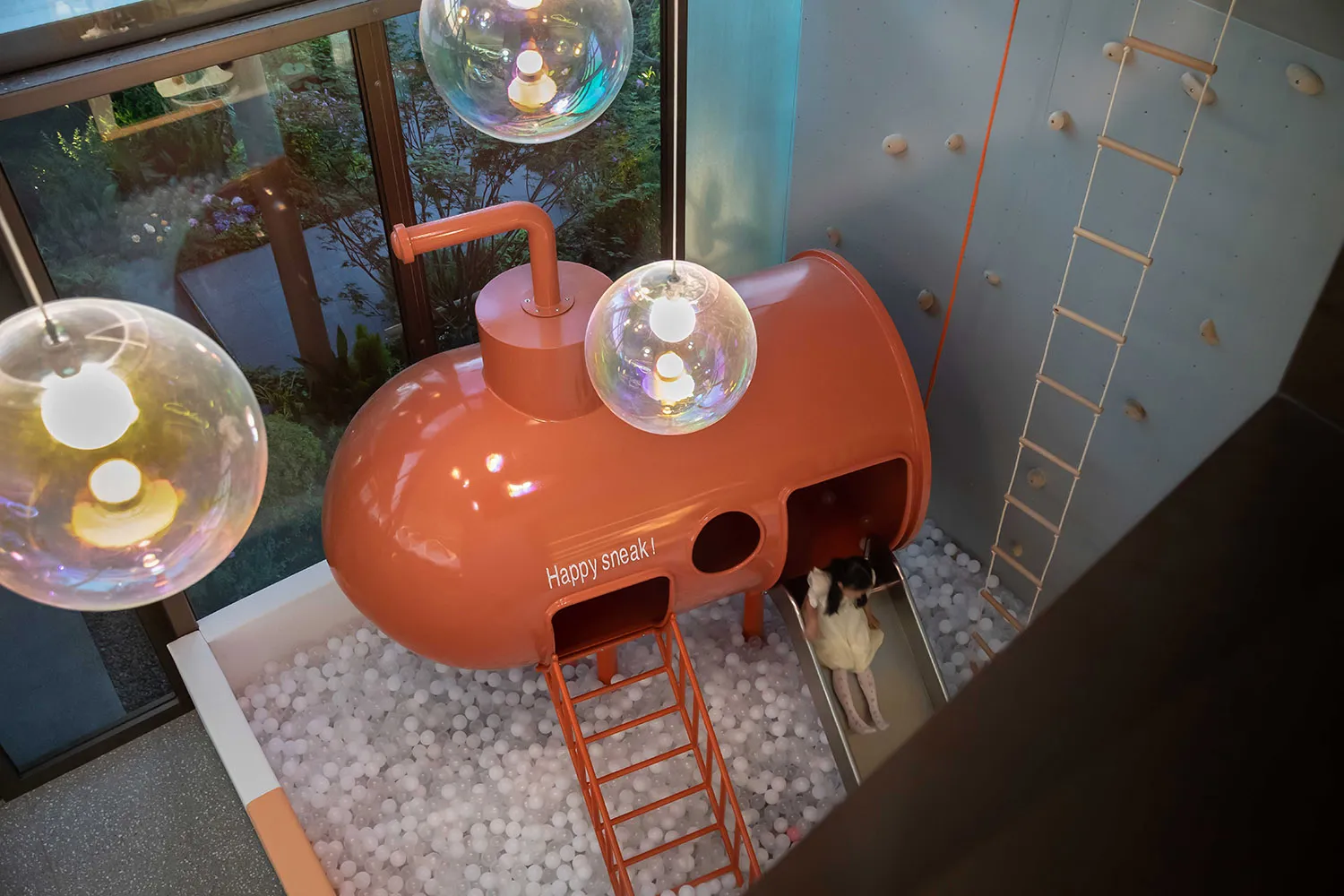 A child emerging from a ball pit slide designed to resemble a submersible