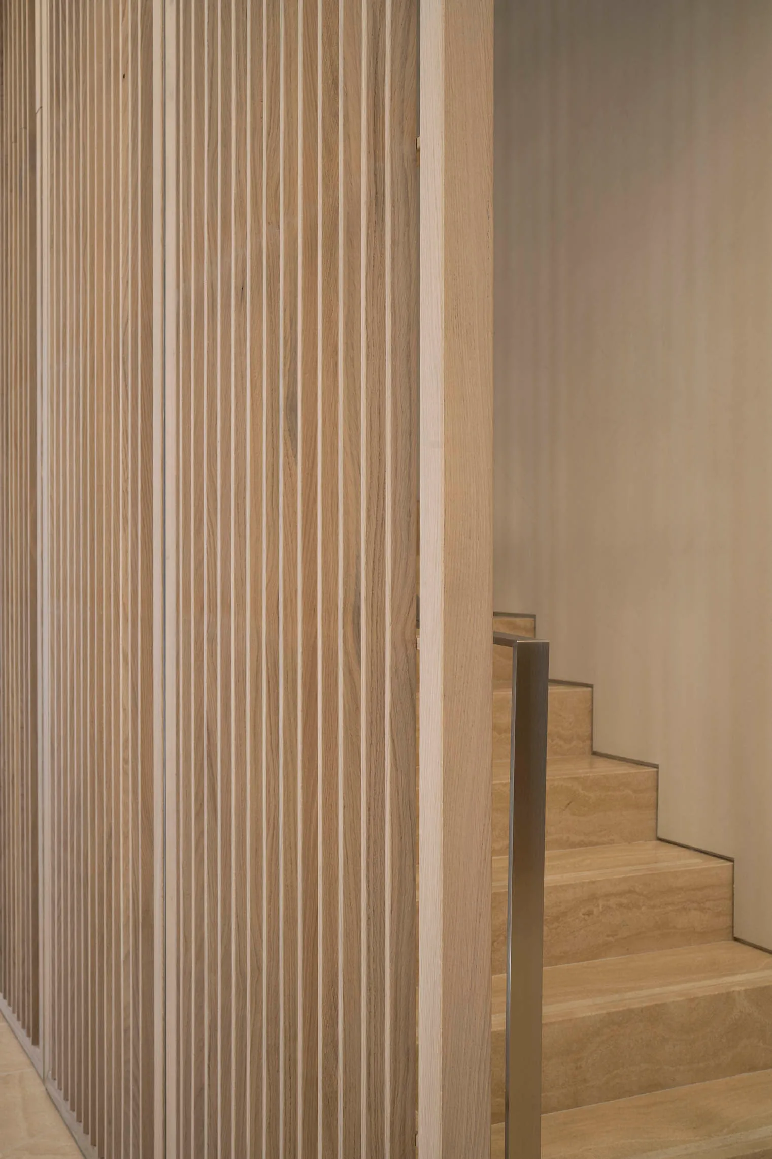 Modern minimalist wooden staircase with vertical slats and metallic handrail
