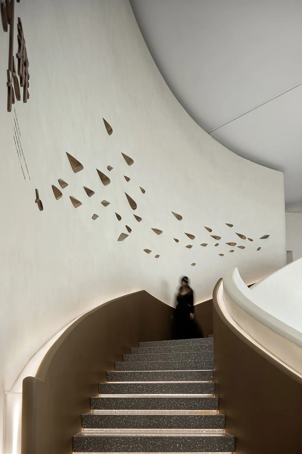 Modern interior featuring a staircase with concrete steps, white textured walls, and abstract artwork resembling dreaming fig