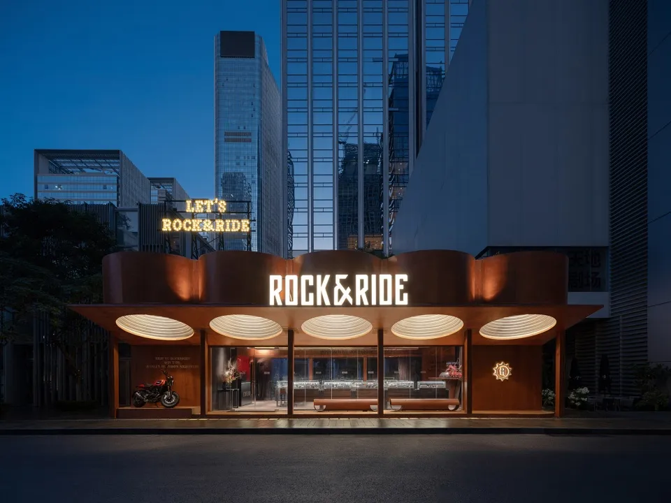 A modern retail storefront with metal cladding and illuminated signage displaying 'ROCK & RIDE'.