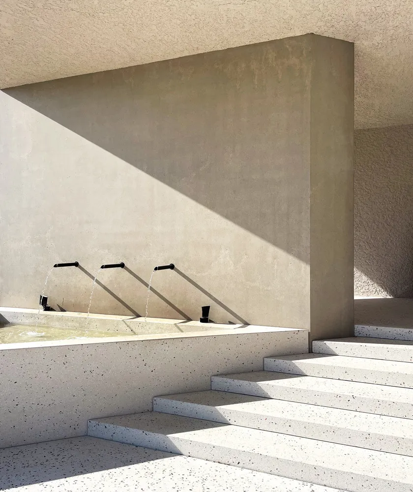 A minimalist outdoor water fountain with concrete and terrazzo materials.