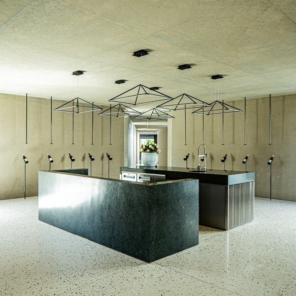 A modern kitchen with a black granite countertop and concrete walls.