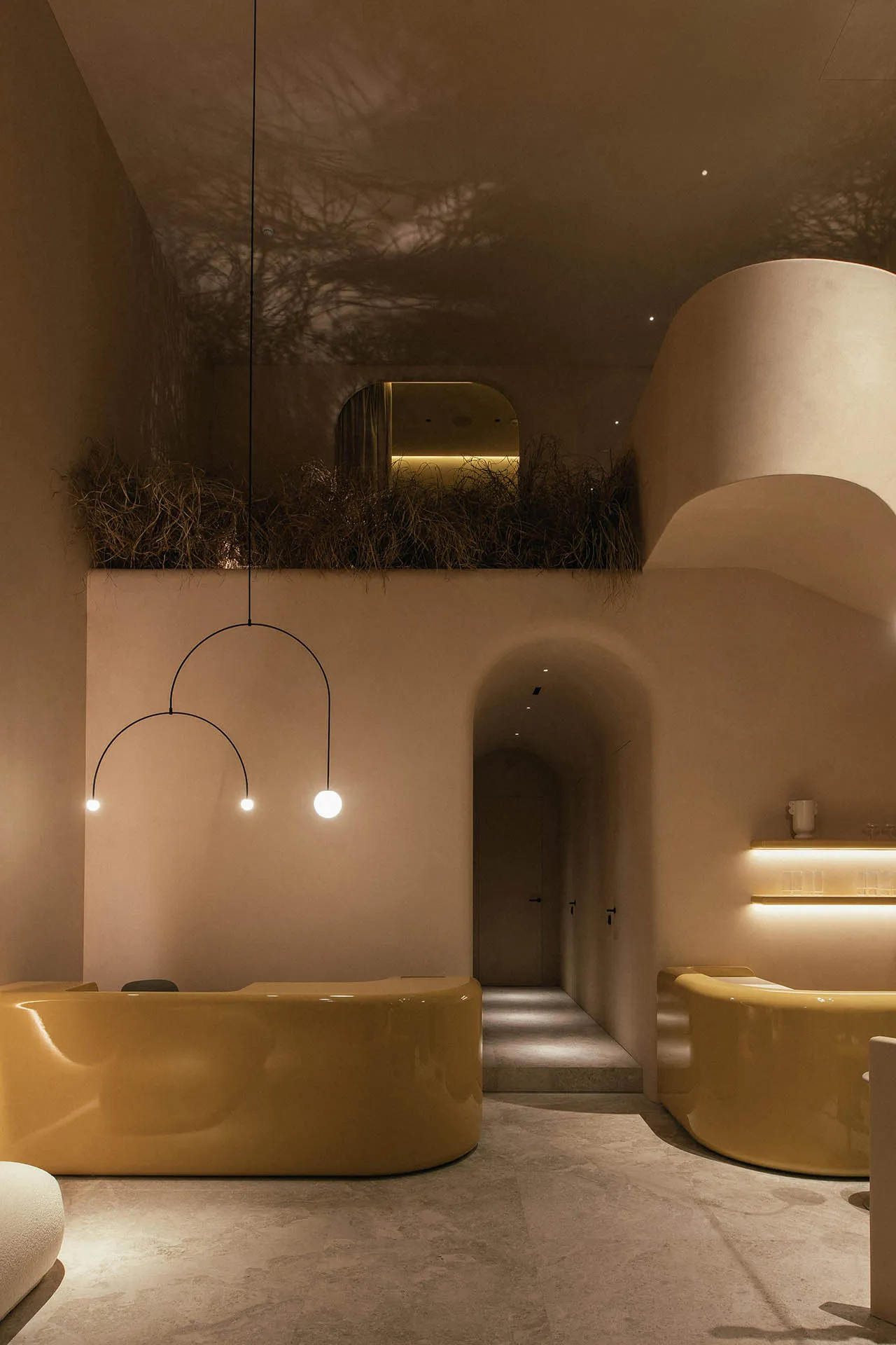 Interior shot of a modern spa with concrete finishes, curved yellow seating, and minimalist lighting.