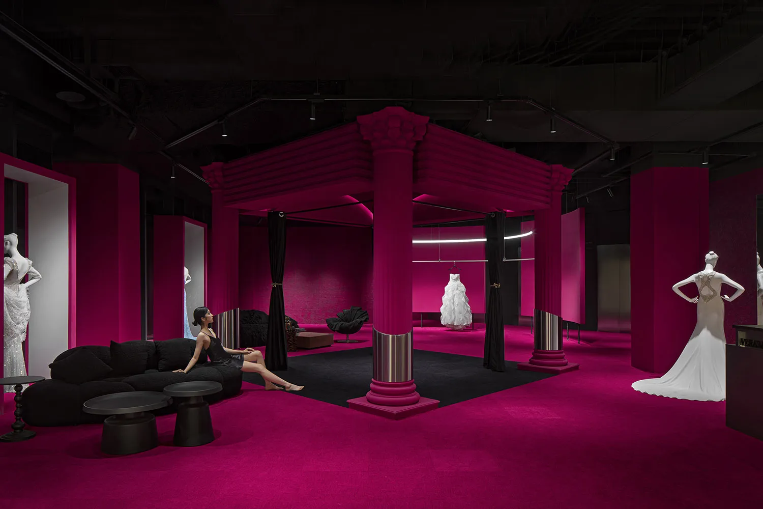 A stylish, fuchsia-themed fashion exhibition space with elegant designs and furniture.