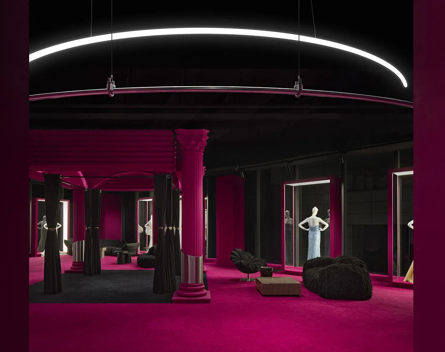 A retail storefront with a vibrant fuchsia color scheme, featuring a high ceiling with a curved LED light fixture and columns