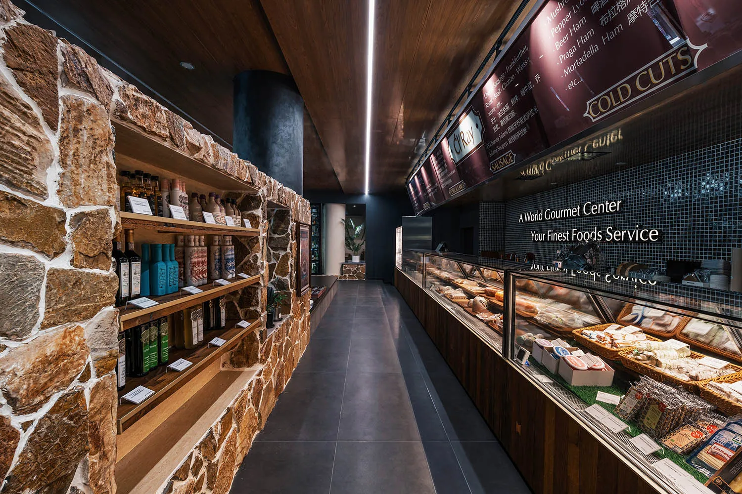 Modern grocery store interior with stone walls, wooden shelves, and illuminated signage.