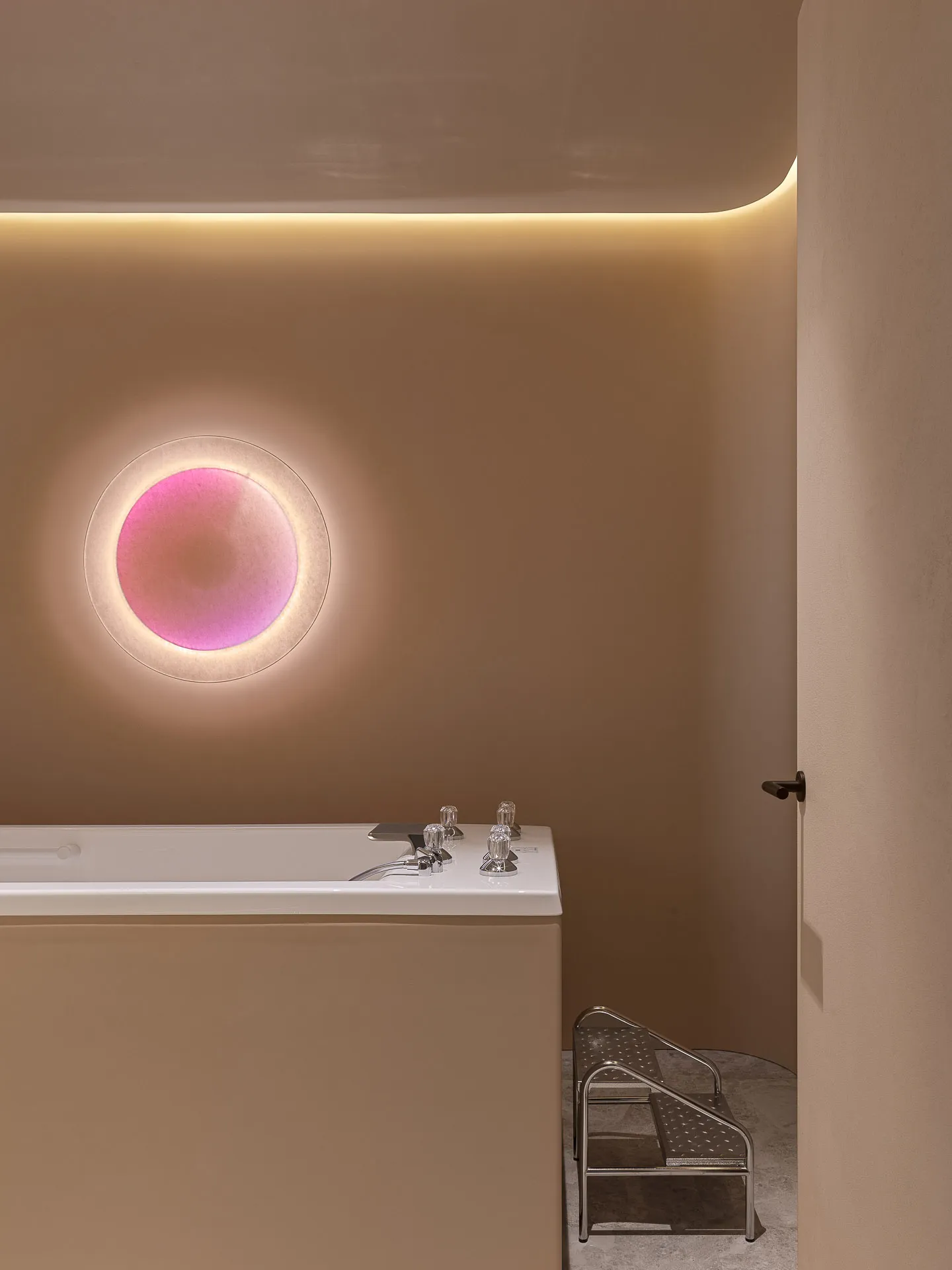 A minimalist bathroom with a round window and plaster walls.