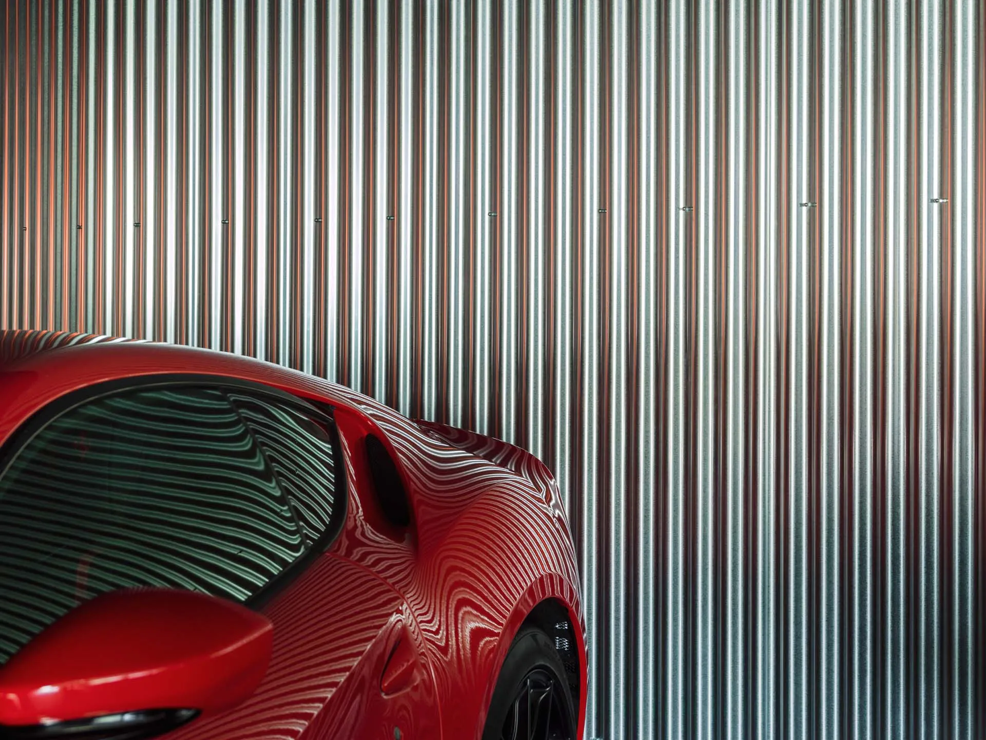 Red car parked beside metallic siding wall