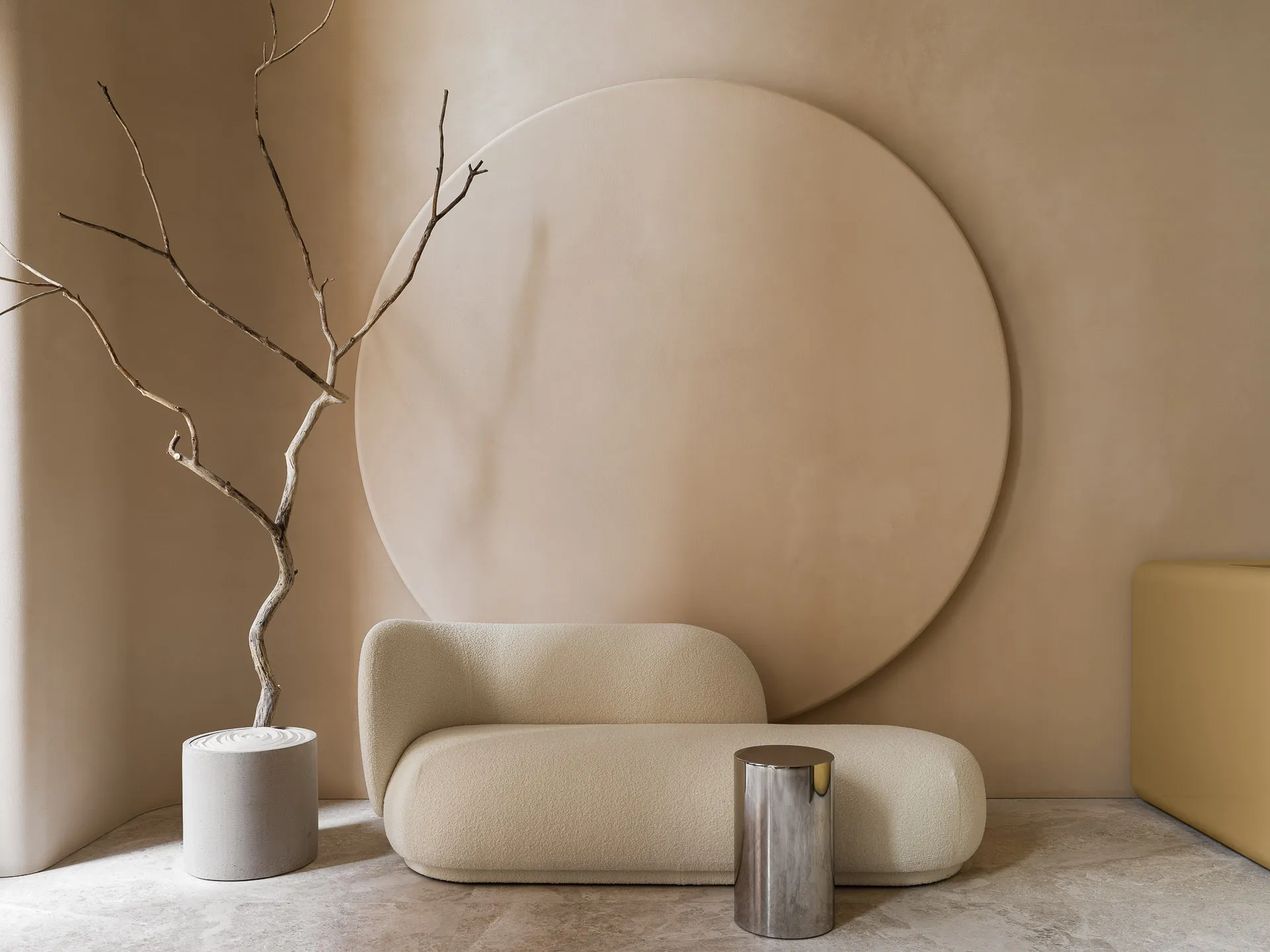 A modern minimalist living room with a beige sofa against a large circular wall panel and a small metallic cylinder on the fl