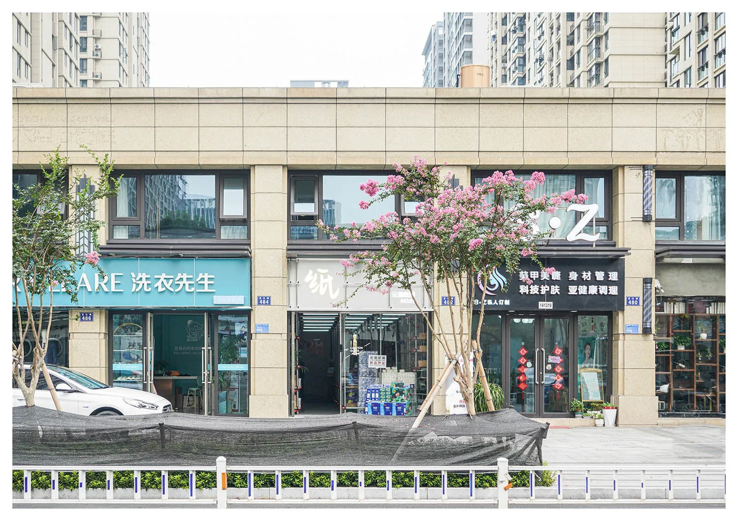 一排現代都市店面,展示各種服務業店家,周圍種植樹木與街道景觀