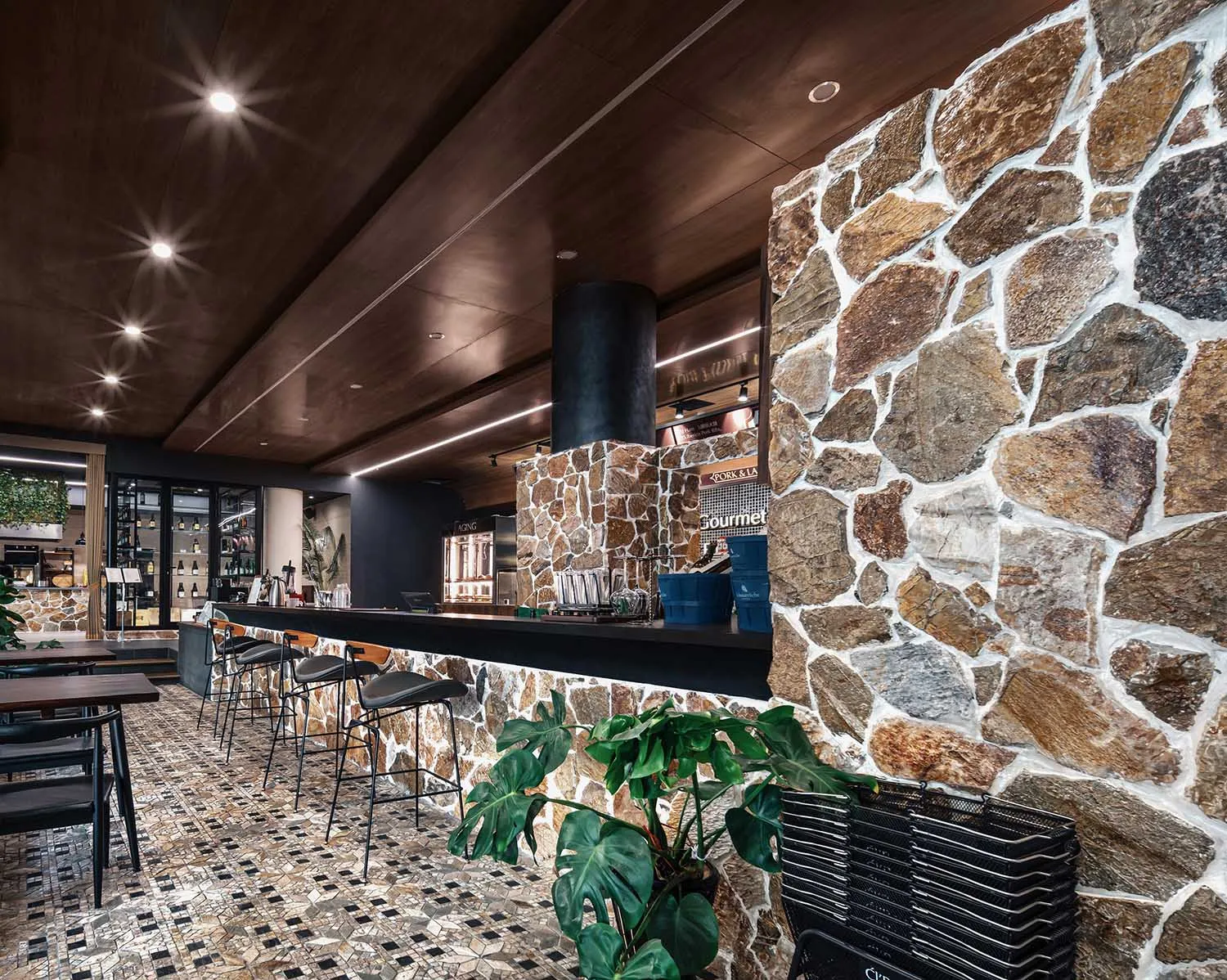 Interior of an industrial-style restaurant featuring a stone bar counter and tiled flooring.