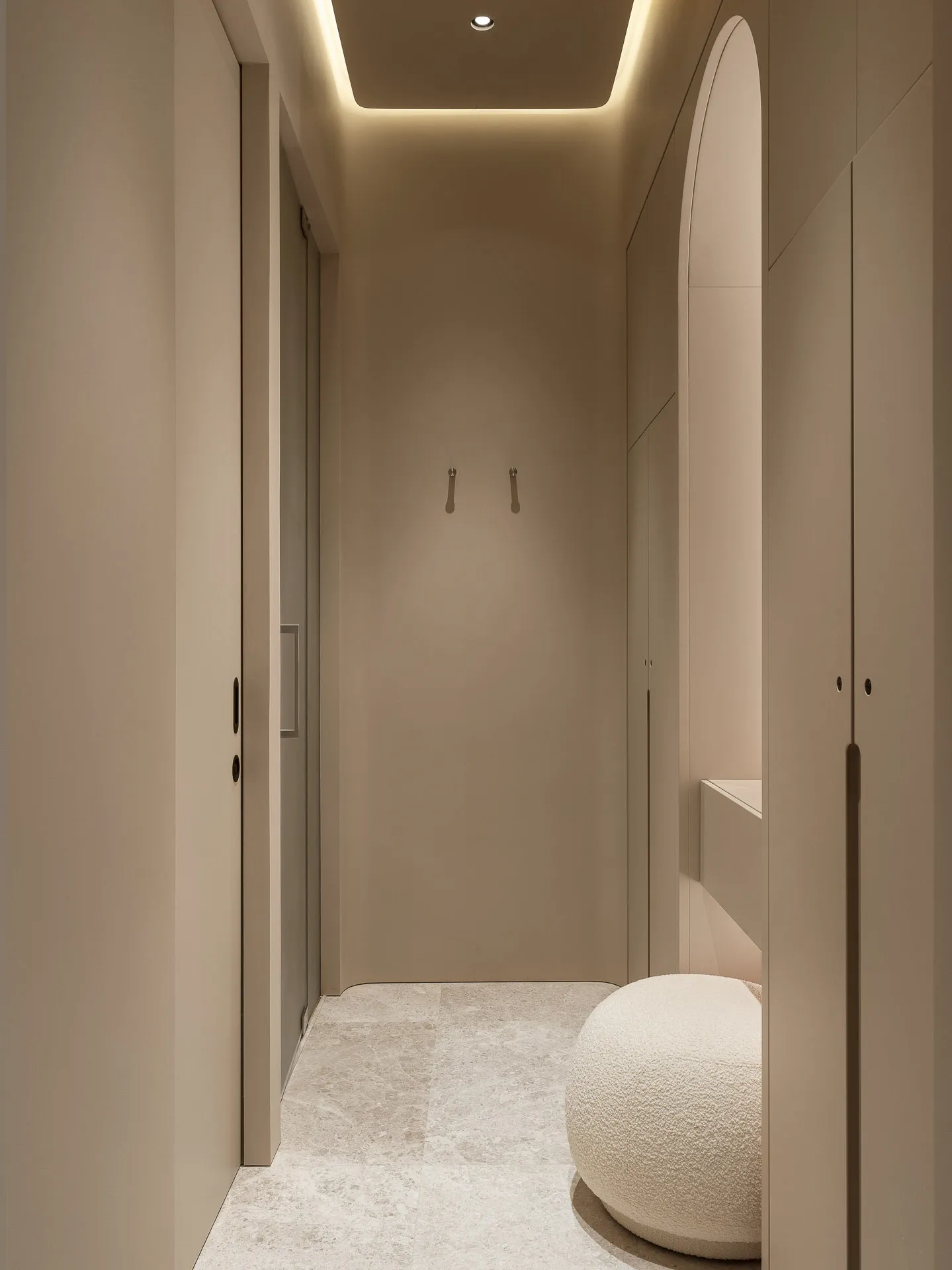 Minimalist corner wardrobe with neutral-toned materials and a cushioned seat.