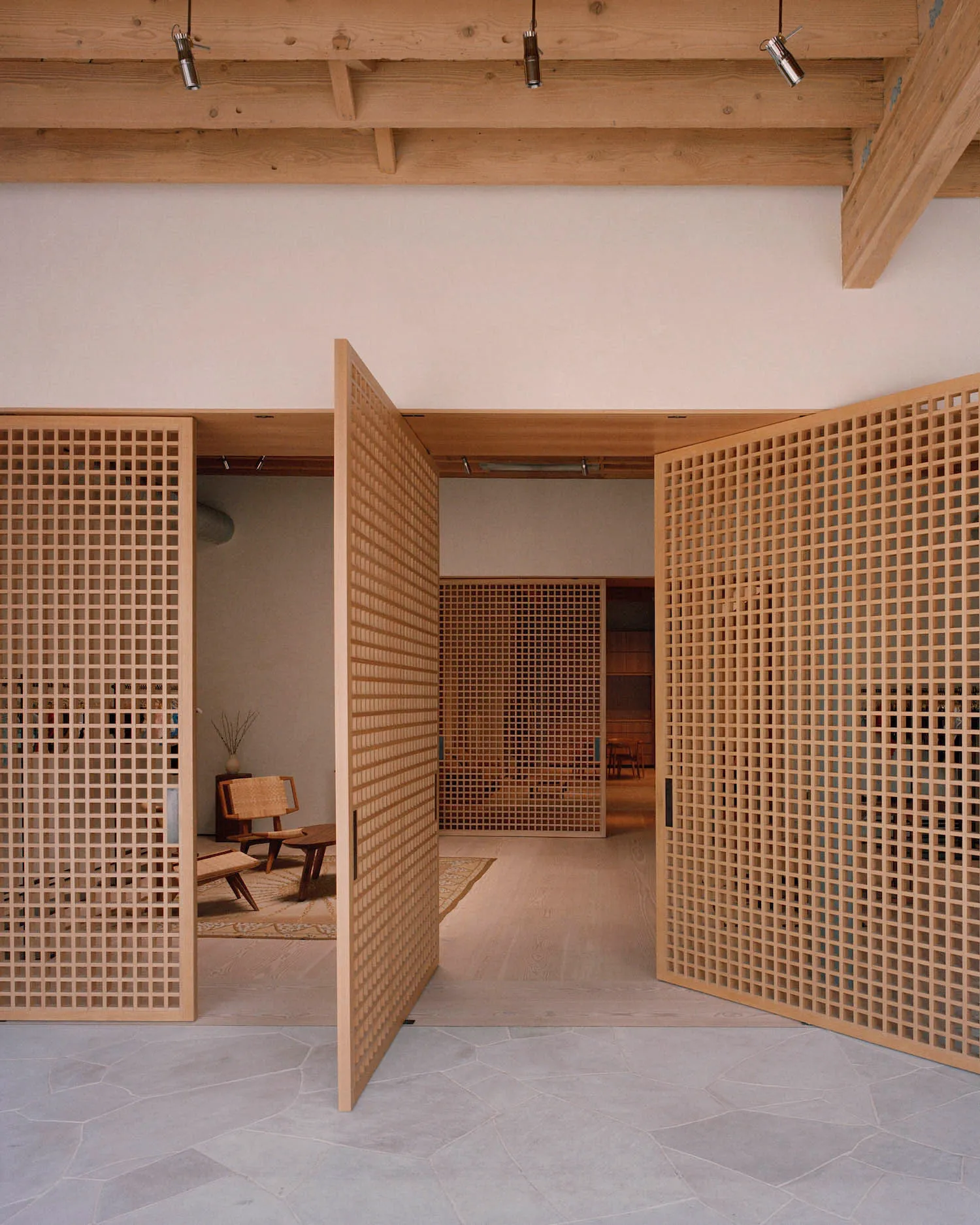 Open wooden lattice doors leading into a minimalist interior design space.