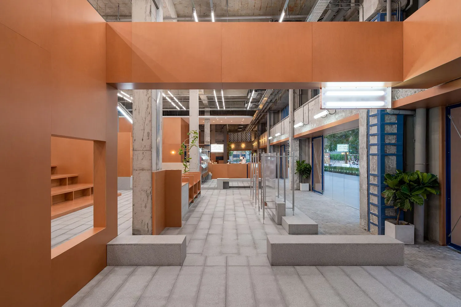 An industrial-style retail store with concrete walls and floors, featuring a modern metal rail and open-plan design.