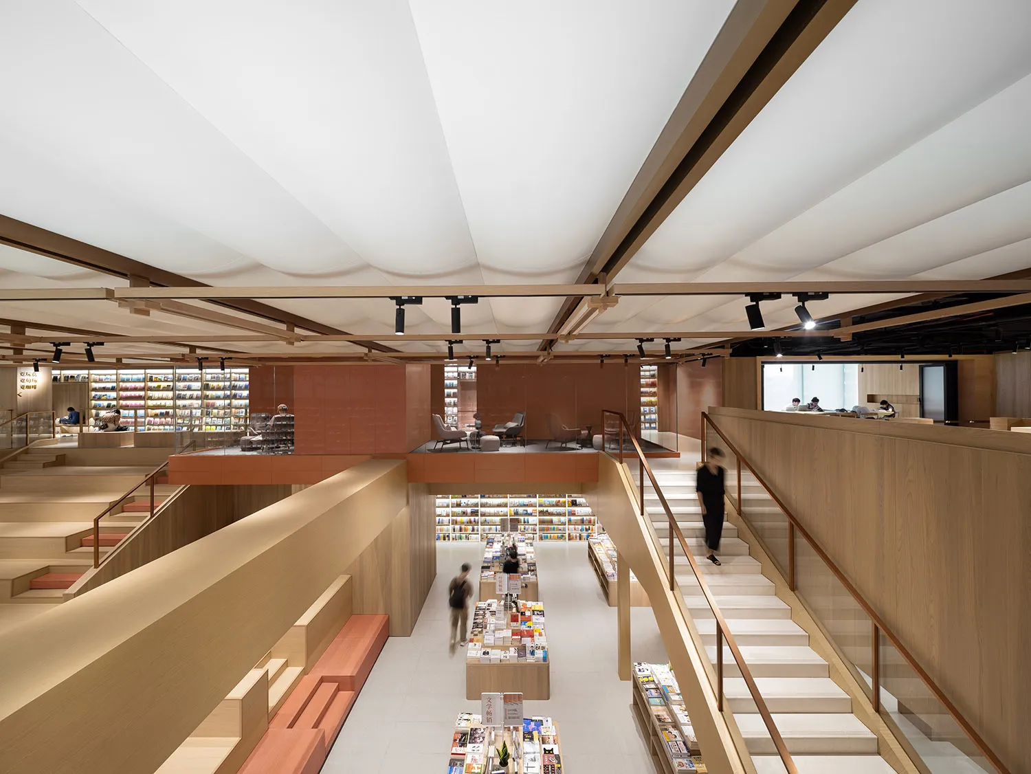 A modern library with wooden structural elements, featuring multiple levels, grand staircases, and a reading area with booksh