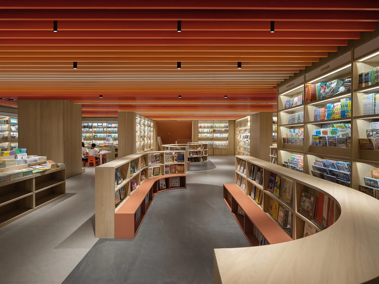 A modern library with shelves of books and reading areas, featuring wood and concrete materials.