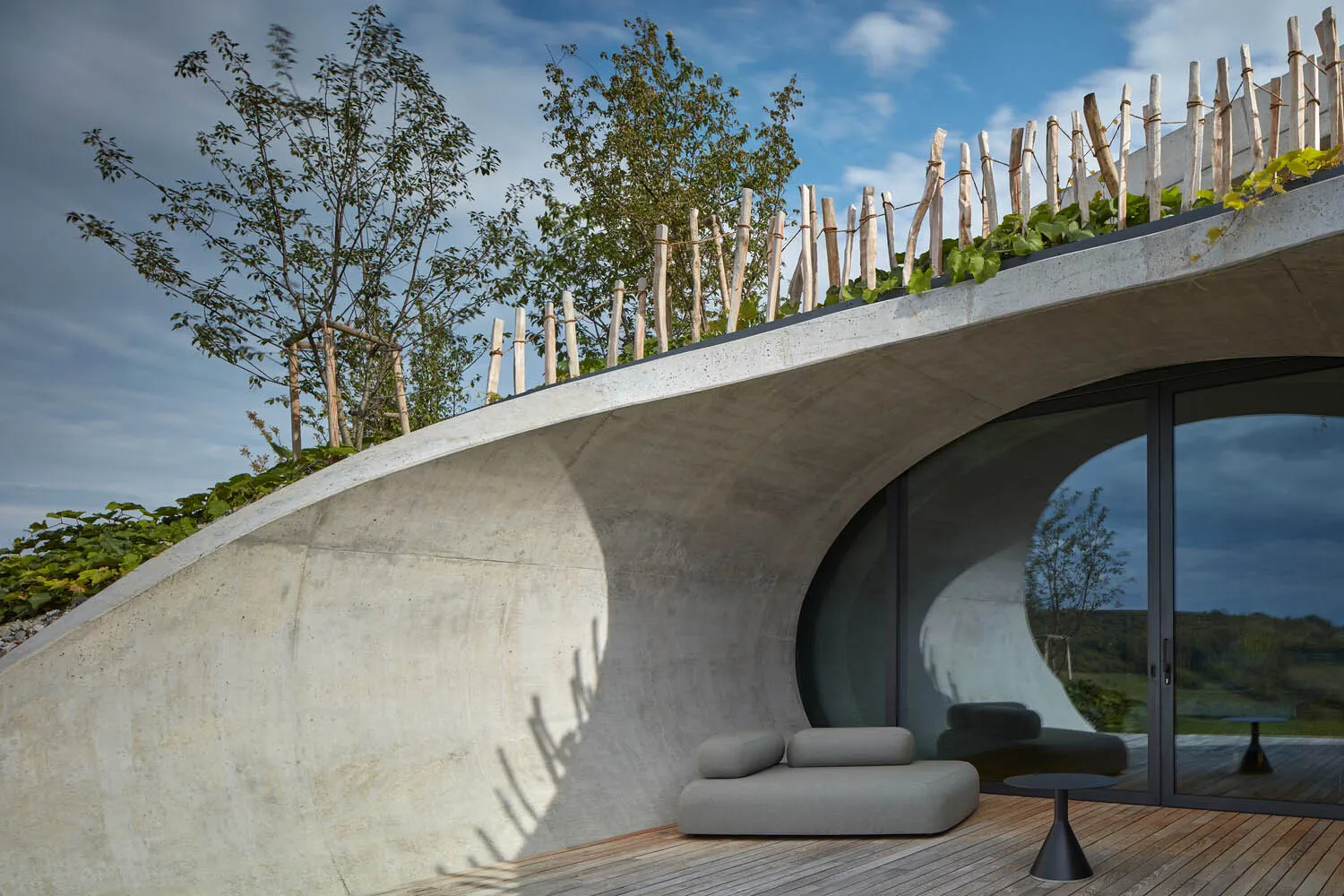 A modern rural house with a concrete roof garden resembling a volcano shelter, featuring natural elements and contemporary de