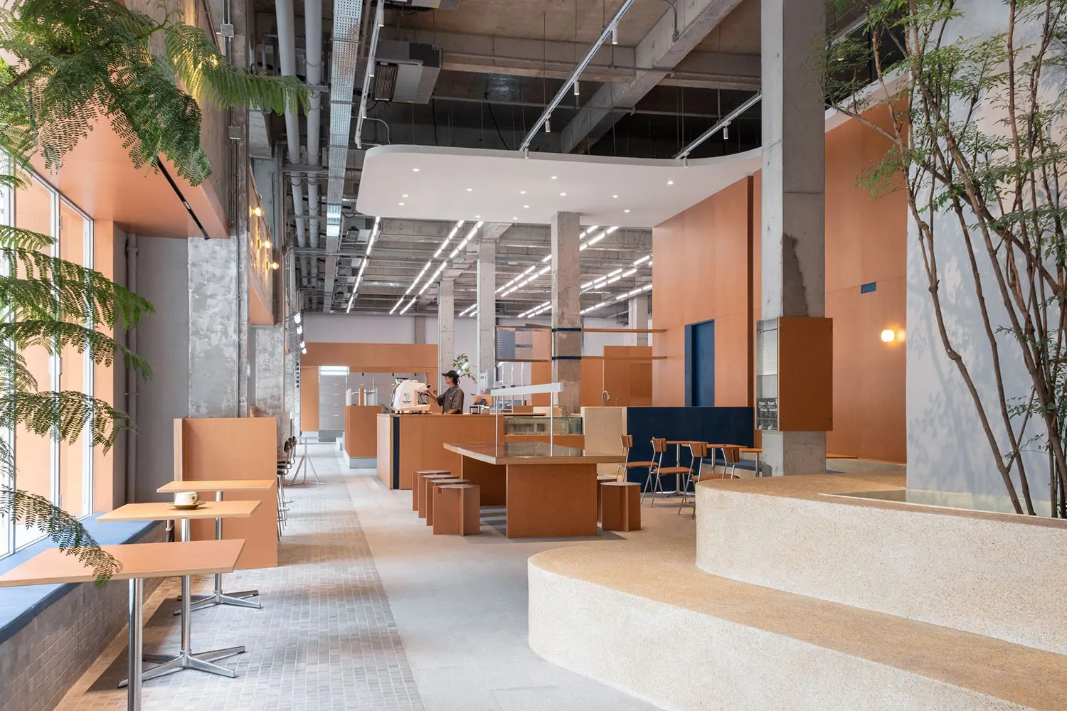 Interior design of a modern industrial coffee shop featuring exposed concrete walls and ceiling.
