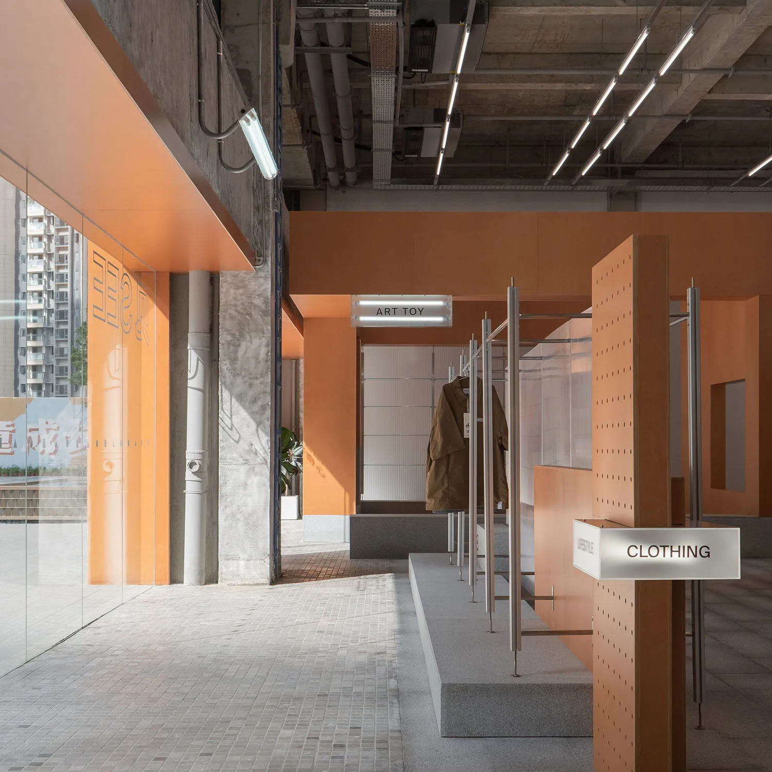 A retail clothing store interior with orange tiled walls and concrete columns