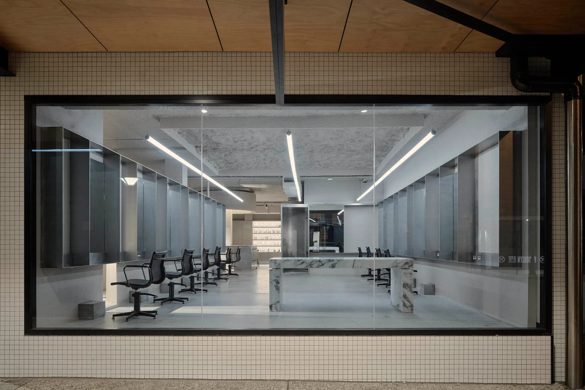 Modern salon interior featuring white marble countertops and chairs, with a minimalist design aesthetic.