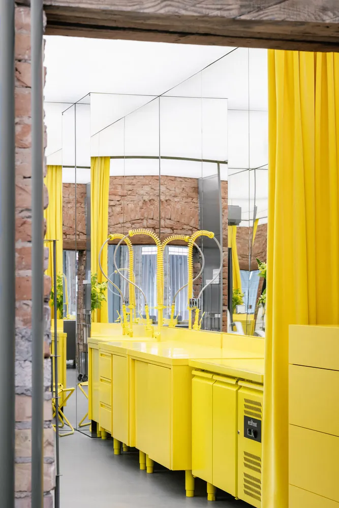 A vibrant commercial interior featuring modern yellow metal cabinets and a mirrored wall.