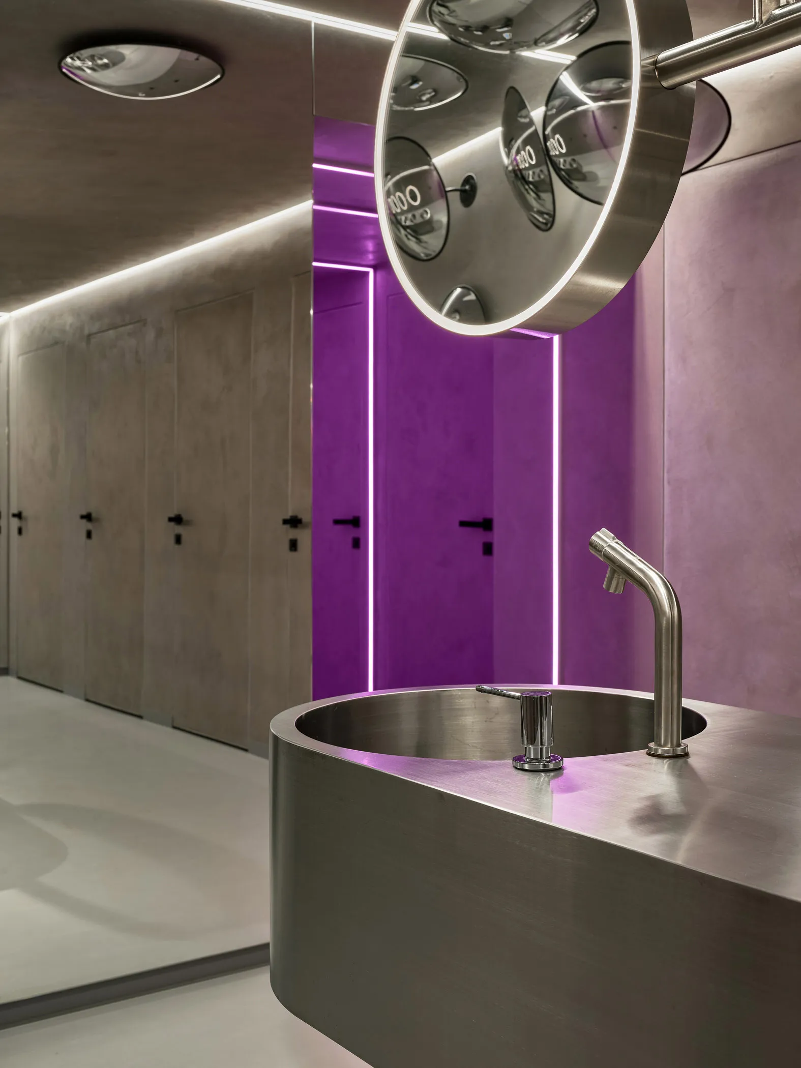 A modern bathroom with a metal sink and purple accents