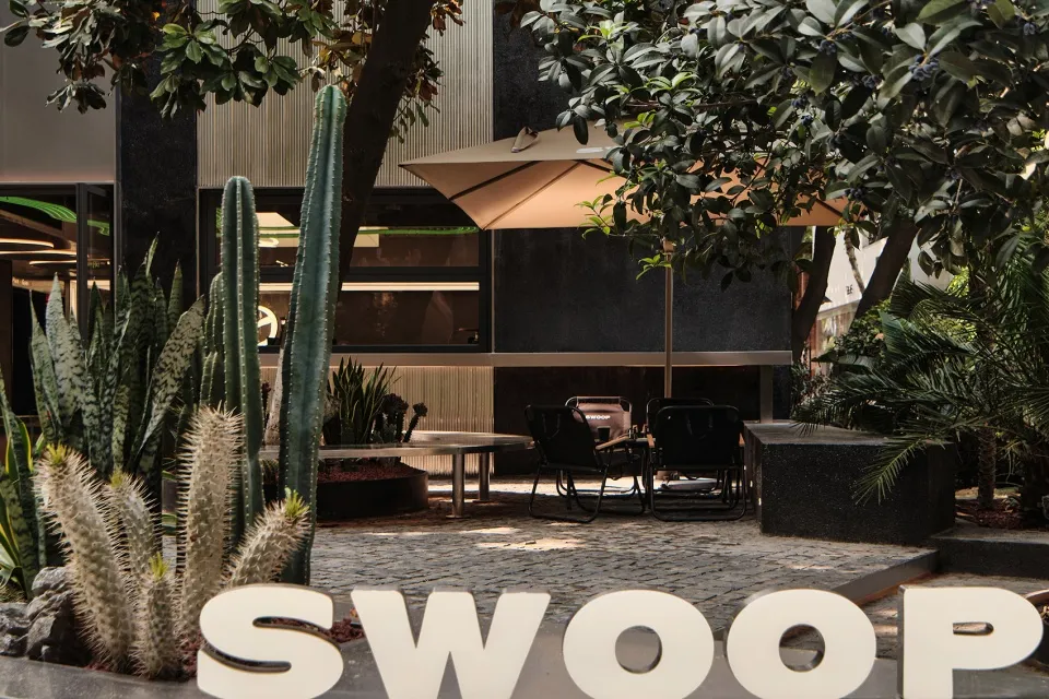 An industrial outdoor patio with concrete flooring, black metal furniture, and plants.