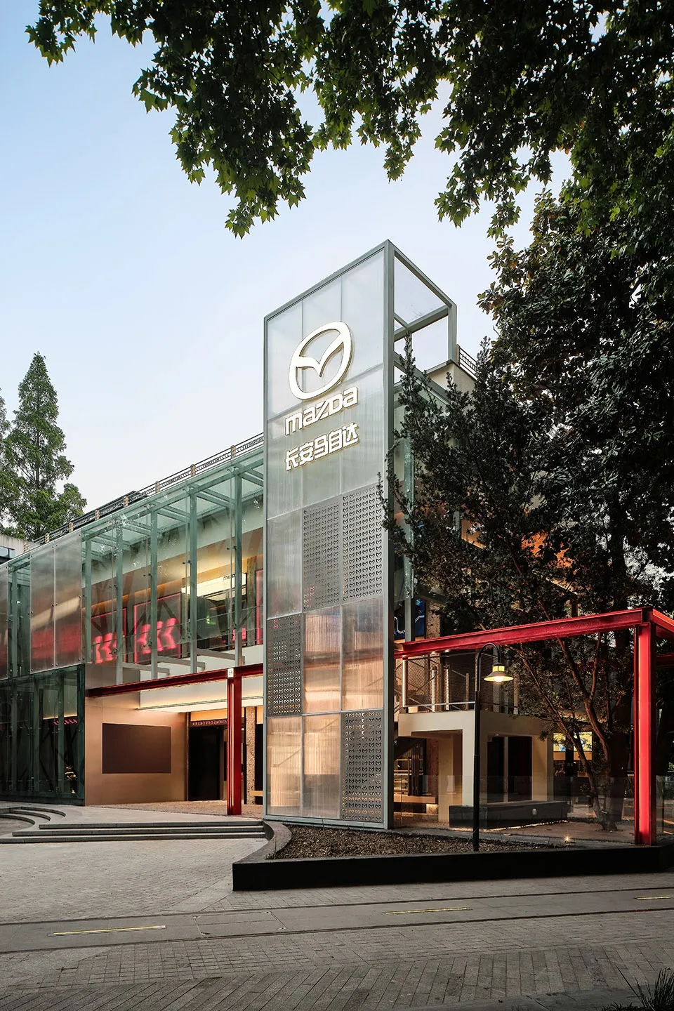 Modern commercial building constructed with glass and aluminum materials, featuring a distinct geometric design.