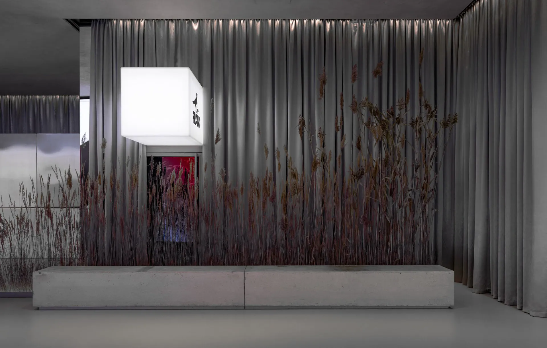 Modern living room featuring concrete furniture, curtains adorned with reeds, and illuminated lighting.