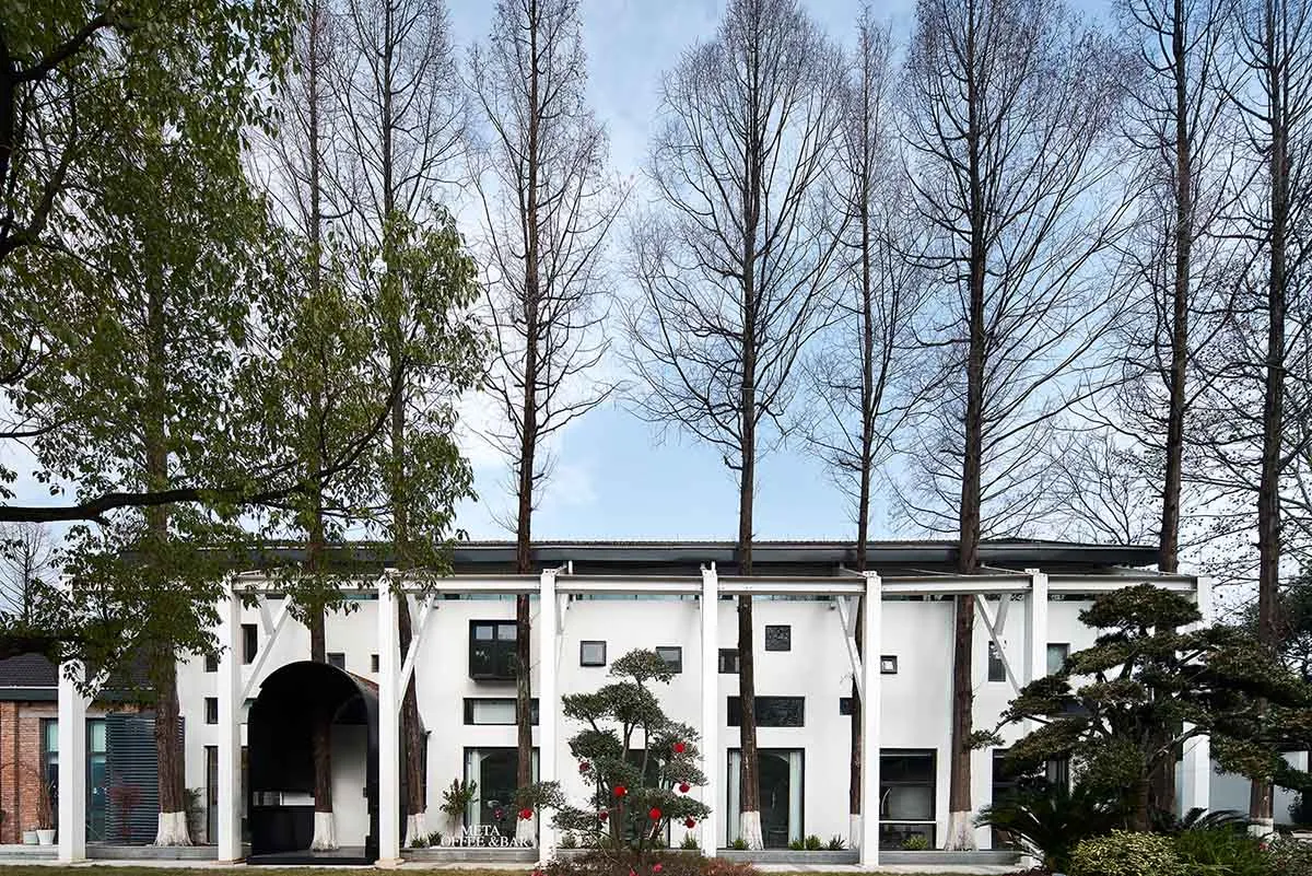 一座現代住宅建築，擁有白色塗料與混凝土外牆，周圍環繞綠意與高大樹木。