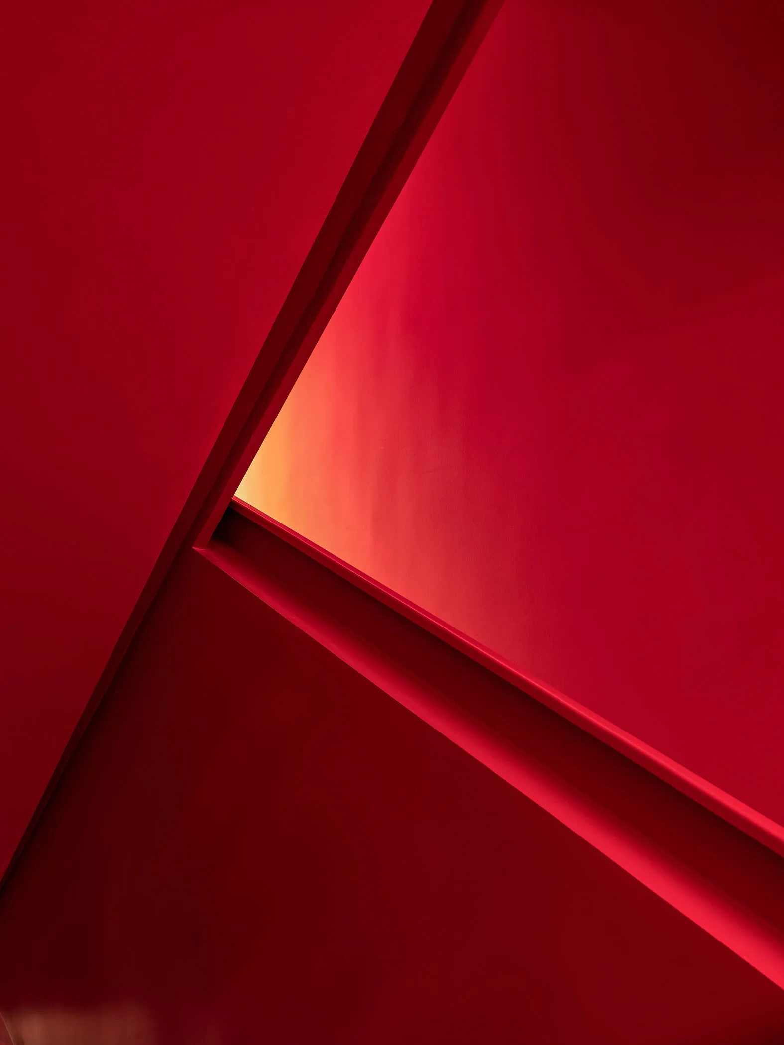 A minimalist interior space with red walls and geometric shapes.