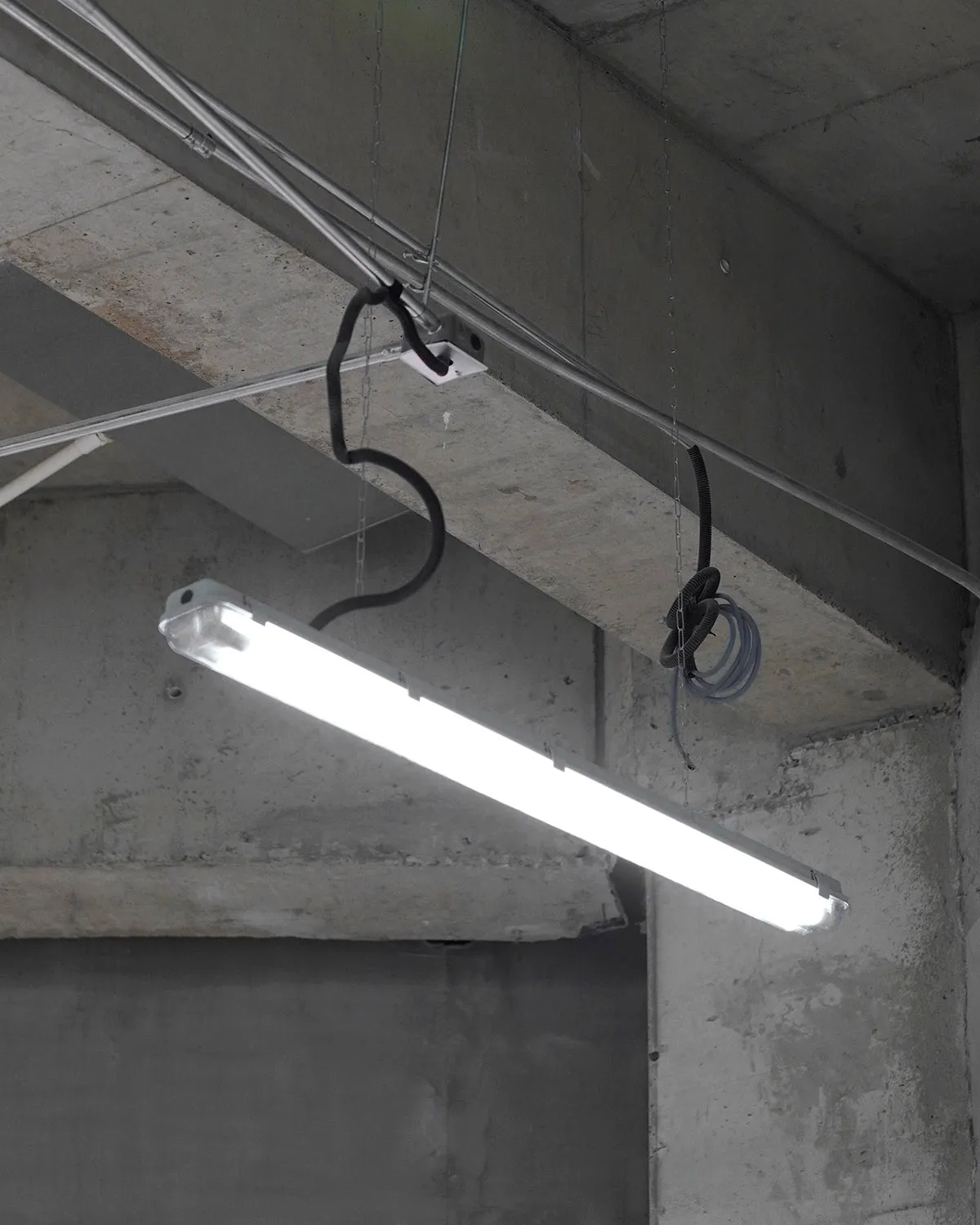 極簡工業風室內空間,混凝土天花板上安裝著一盞螢光燈具。