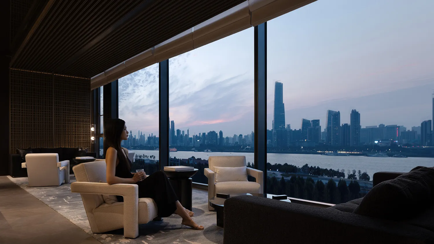 現代客廳搭配玻璃窗,窗外俯瞰城市景觀,正值日落時分。