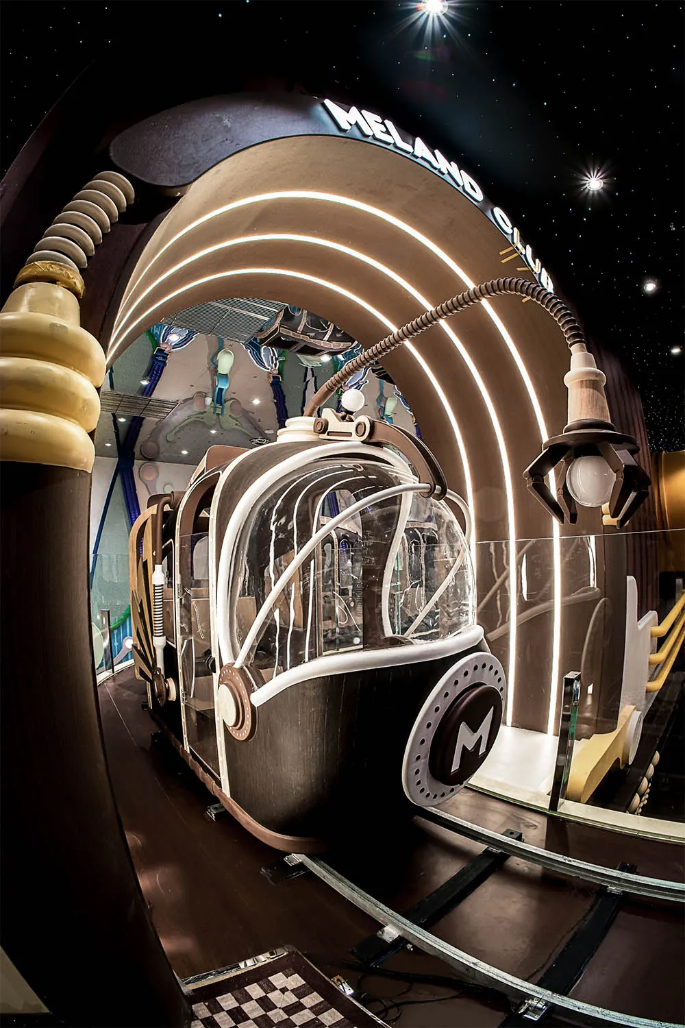 A futuristic glass structure with a curved, space-themed exterior resembling a spaceship or piece of architecture.