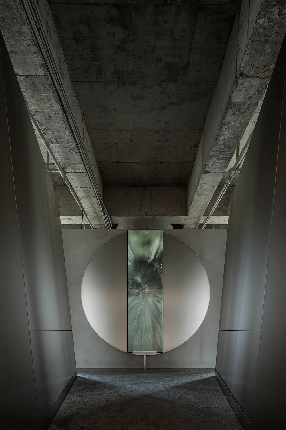 Modern lobby with a circular concrete wall and a glass panel on the ceiling.