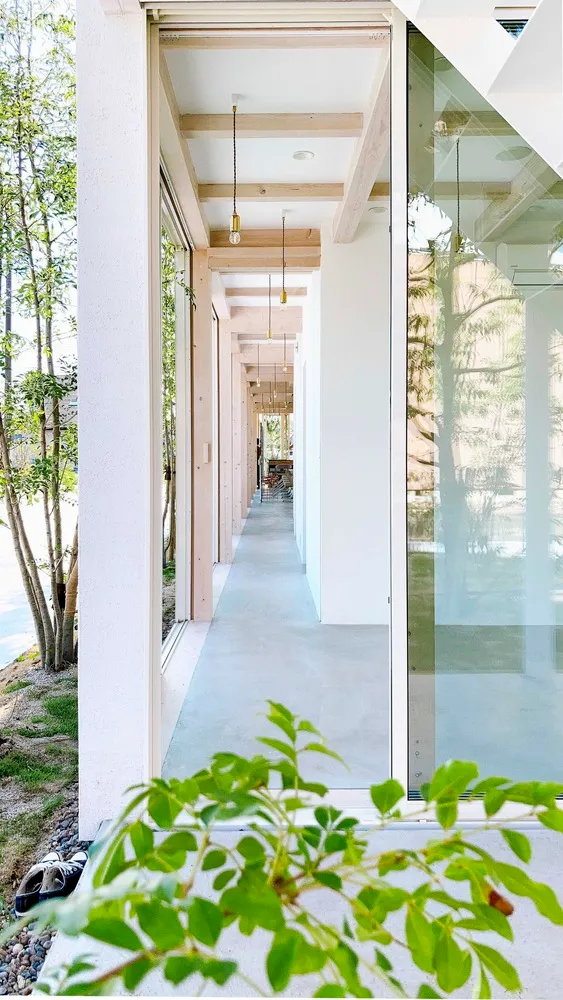 A minimalist modern hallway with concrete flooring, large windows, and exposed wooden beams.