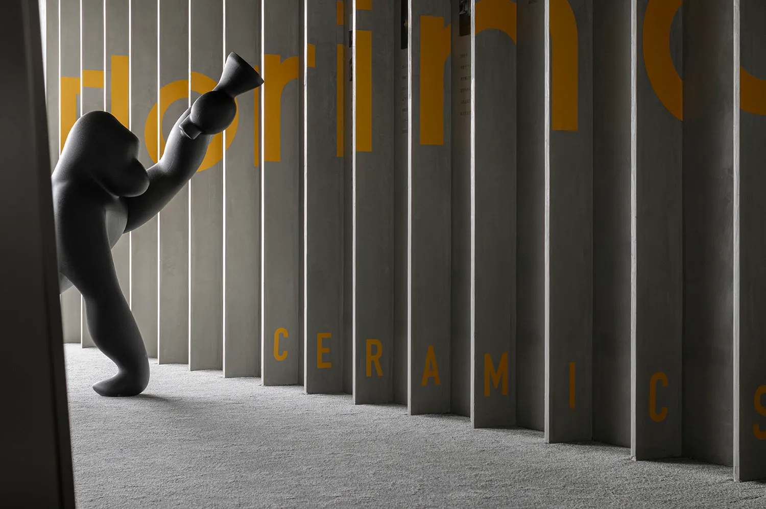 A modern ceramic object displayed against a grey, concrete wall with yellow text reading "ceramics."