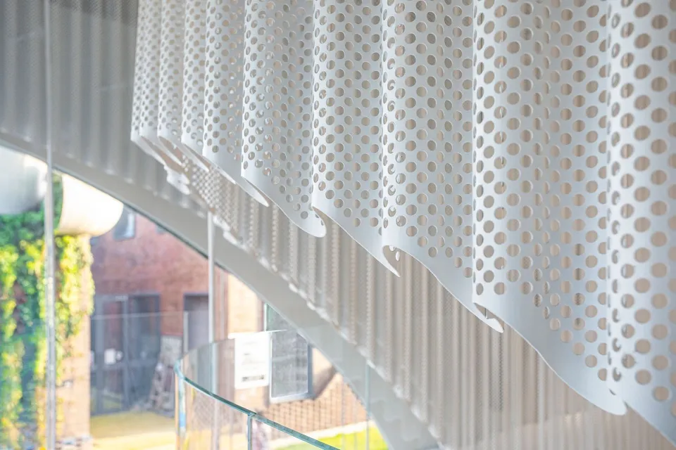 A close-up view of modern interior design featuring a metal perforated screen with a geometric pattern.