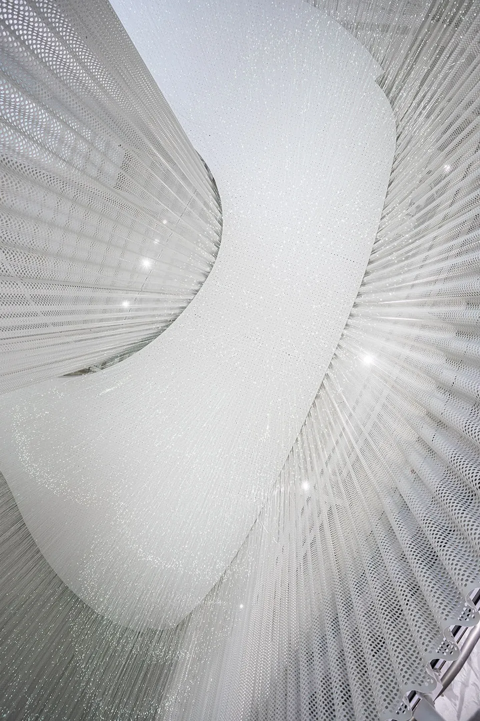 A modern textile lighting installation featuring soft, white light and intricate, cylindrical shapes.